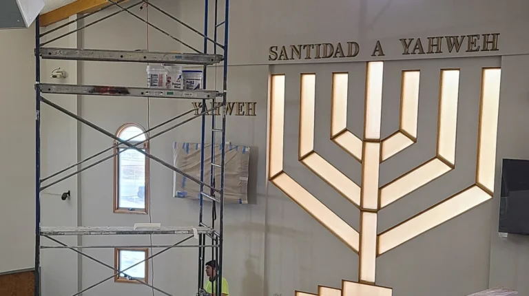 Scaffolding beside lit menorah display and Santidad A Yahweh sign in worship space