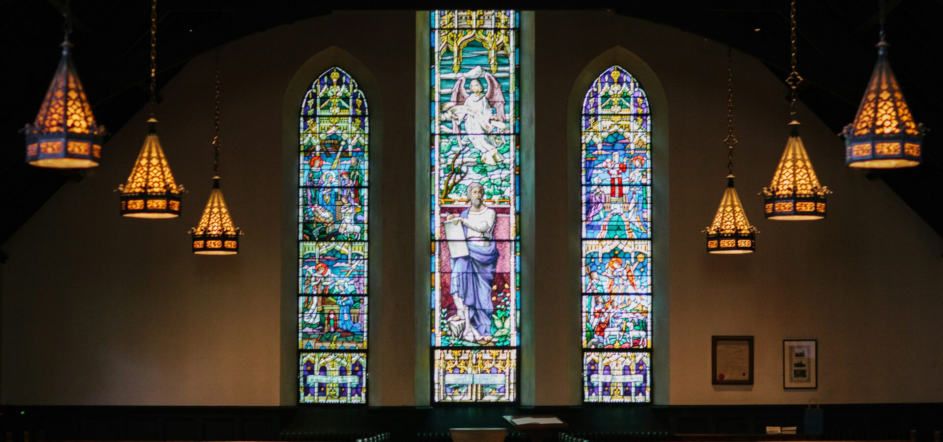 Church sanctuary interior with pews near stained glass windows