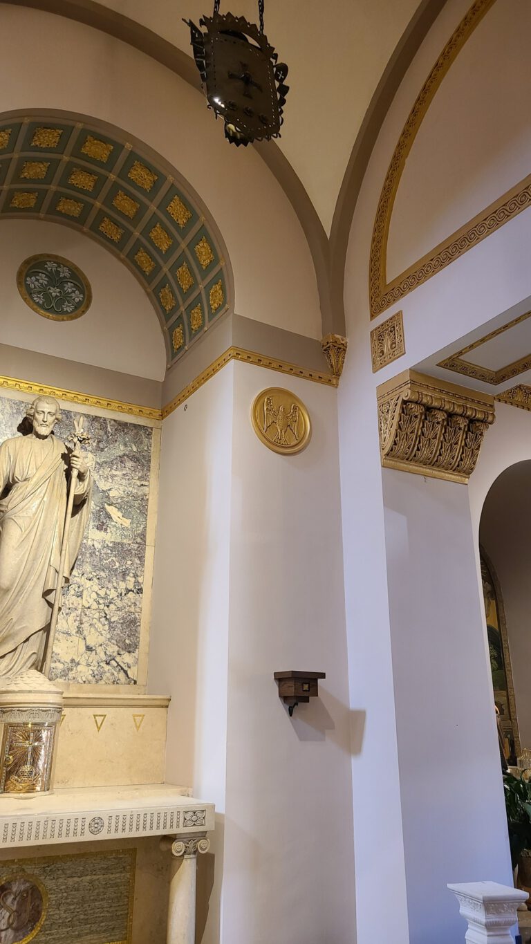 Ornate church interior showing painted arched alcove, gold moldings, and religious artwork