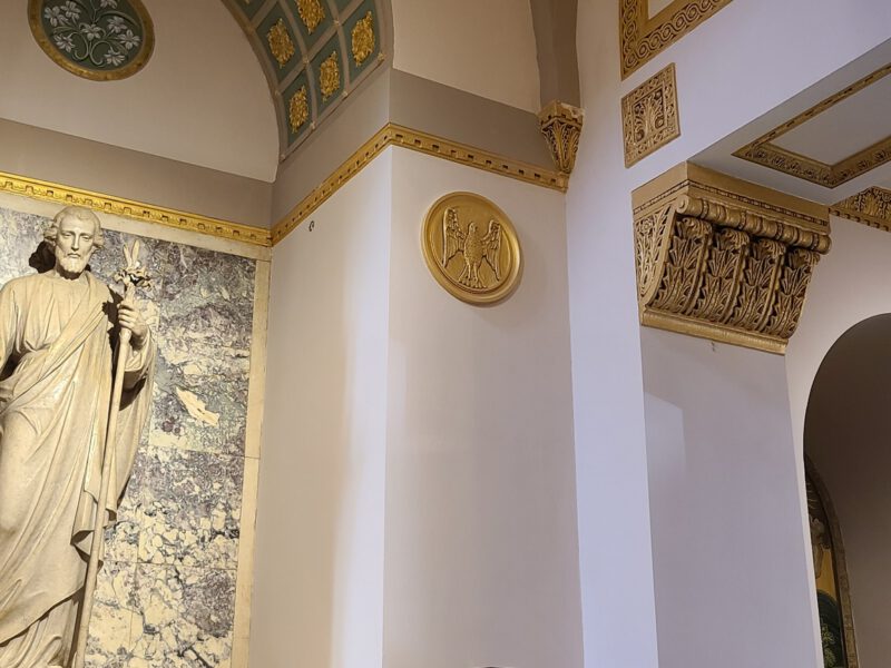 Ornate church interior showing painted arched alcove, gold moldings, and religious artwork