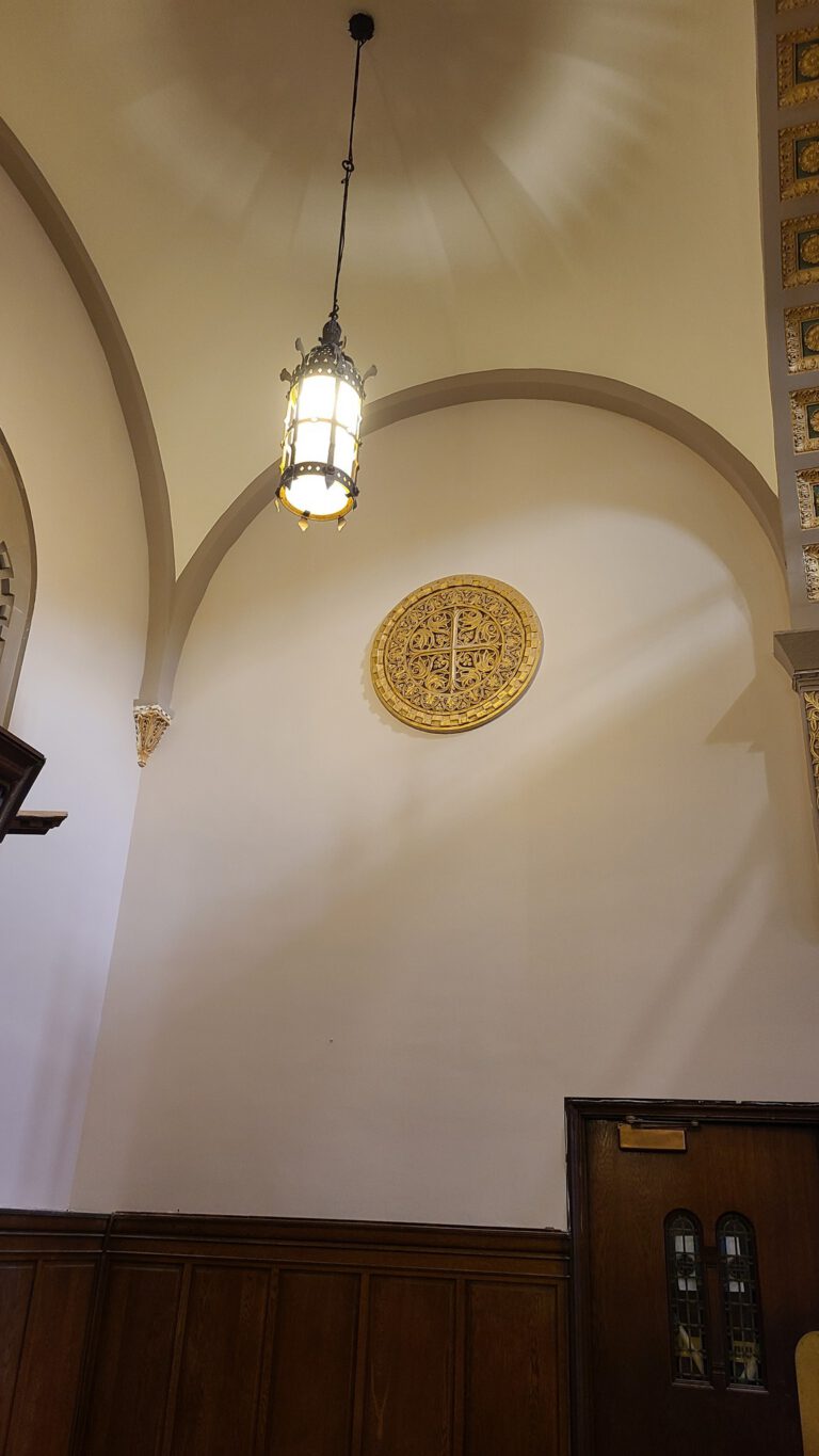 Stone arched entryway with ornate medallion and hanging lantern in house of worship